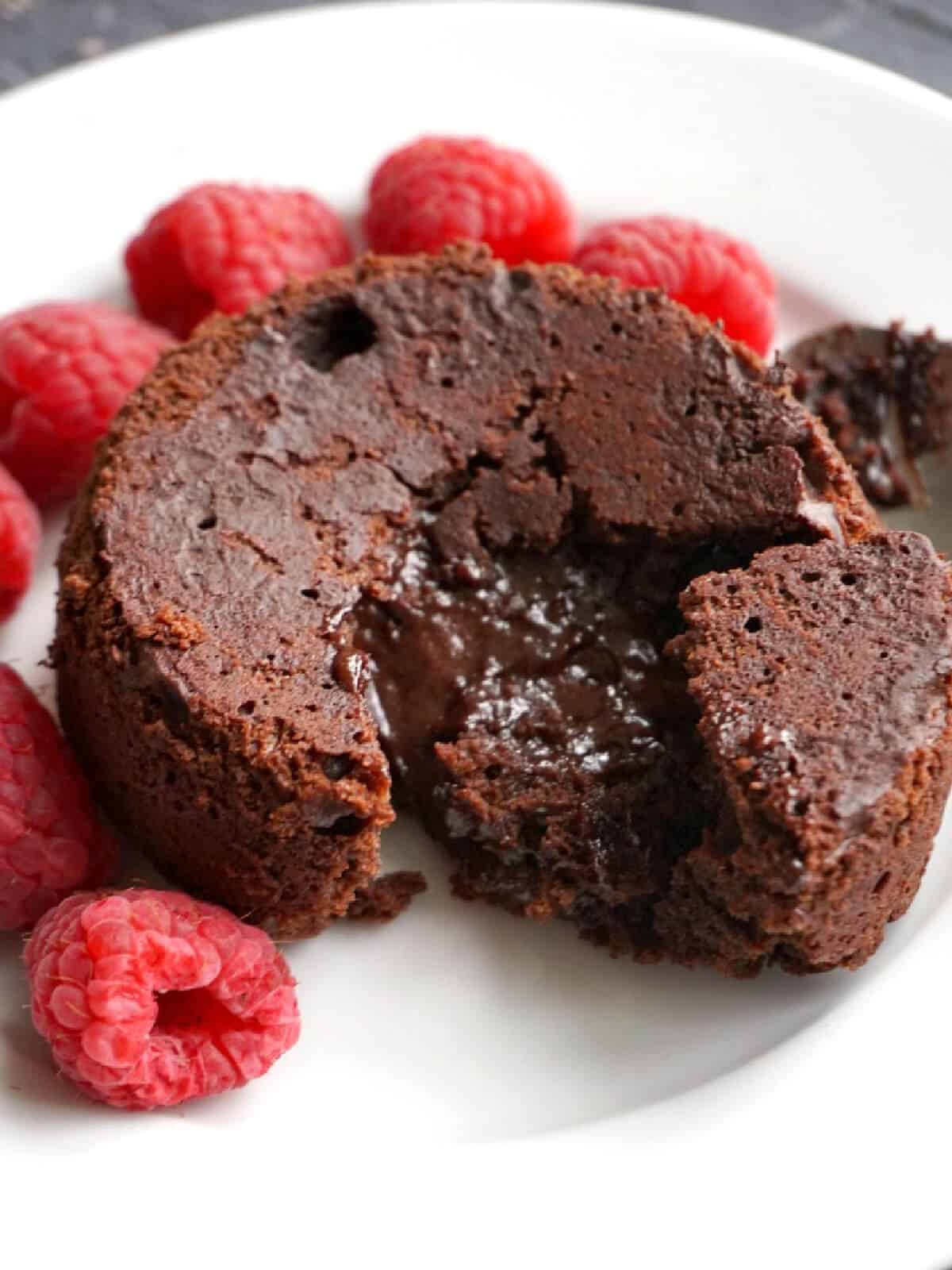 A mini chocolate cake surrounded by raspberries.