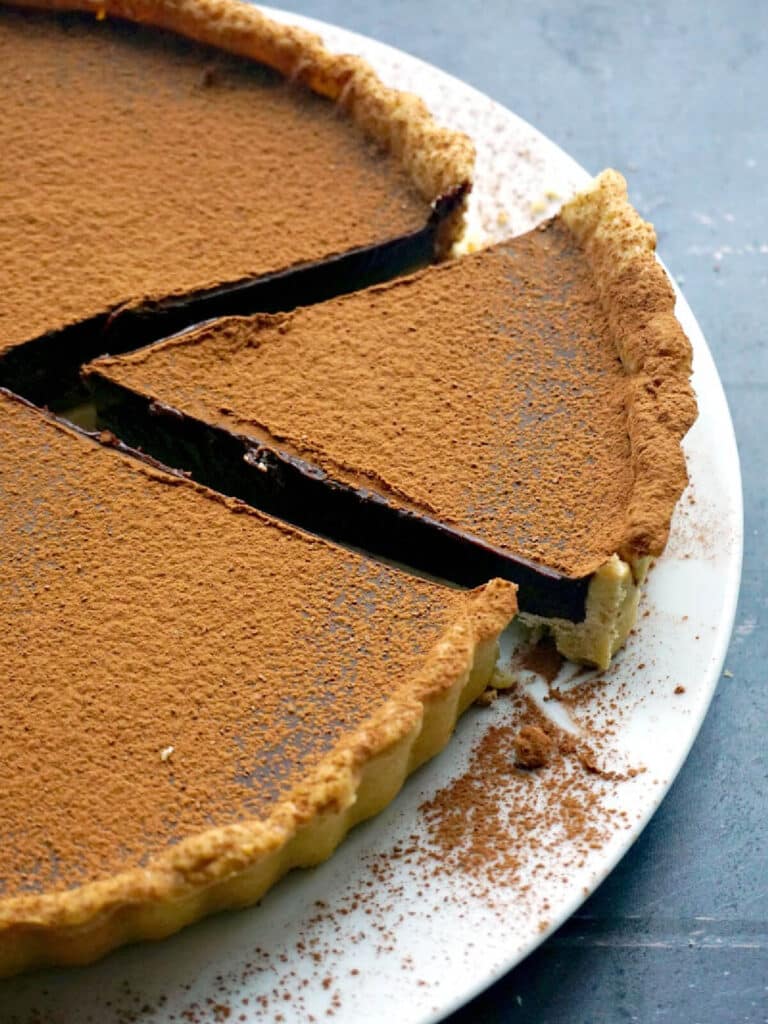 A white plate with a sliced chocolate tart