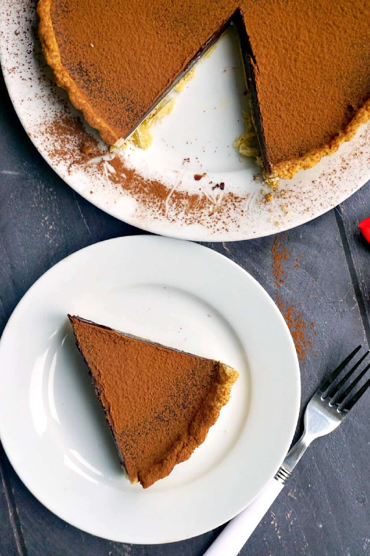 Overhead shoot of a white plate with a slice of chocolate tart and another plate with the rest of the tart