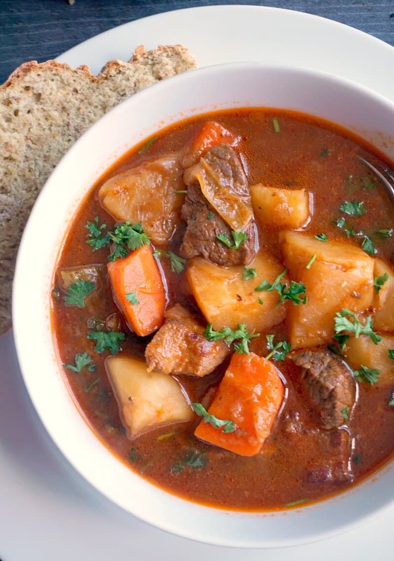 Overhead shoot of a white bowl with guinness beef stew and veggies.