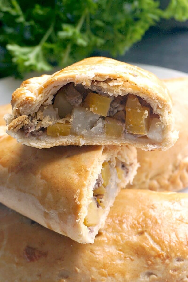 Half of a cornish pasty on top of another half pasty and two whole pasties