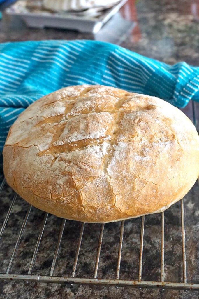 A round crusty bread on a cooling rack