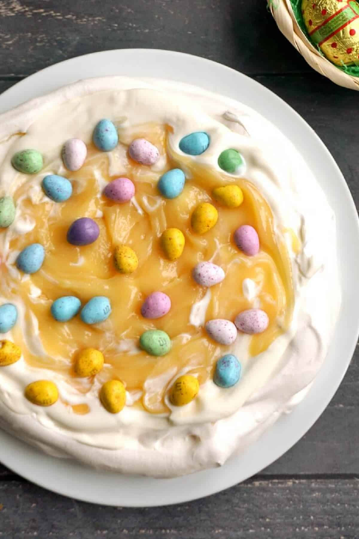 Overhead shoot of a pavlova with lemon curd and mini chocolate eggs.