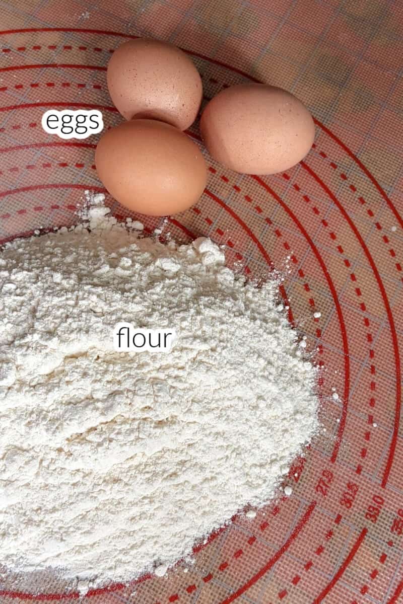 A tabletop with 3 eggs and flour.