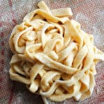 A nest of fresh fettuccine pasta on a tabletop.