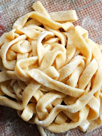 A nest of fresh fettuccine pasta on a tabletop.