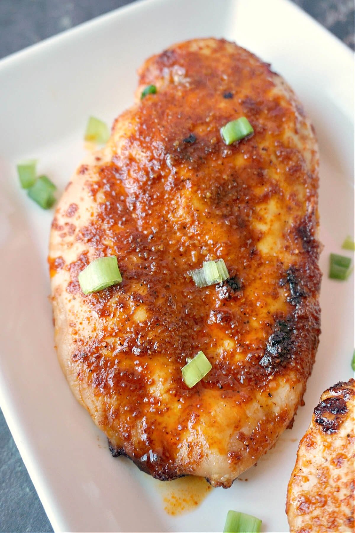 A white plate with a baked chicken breast.