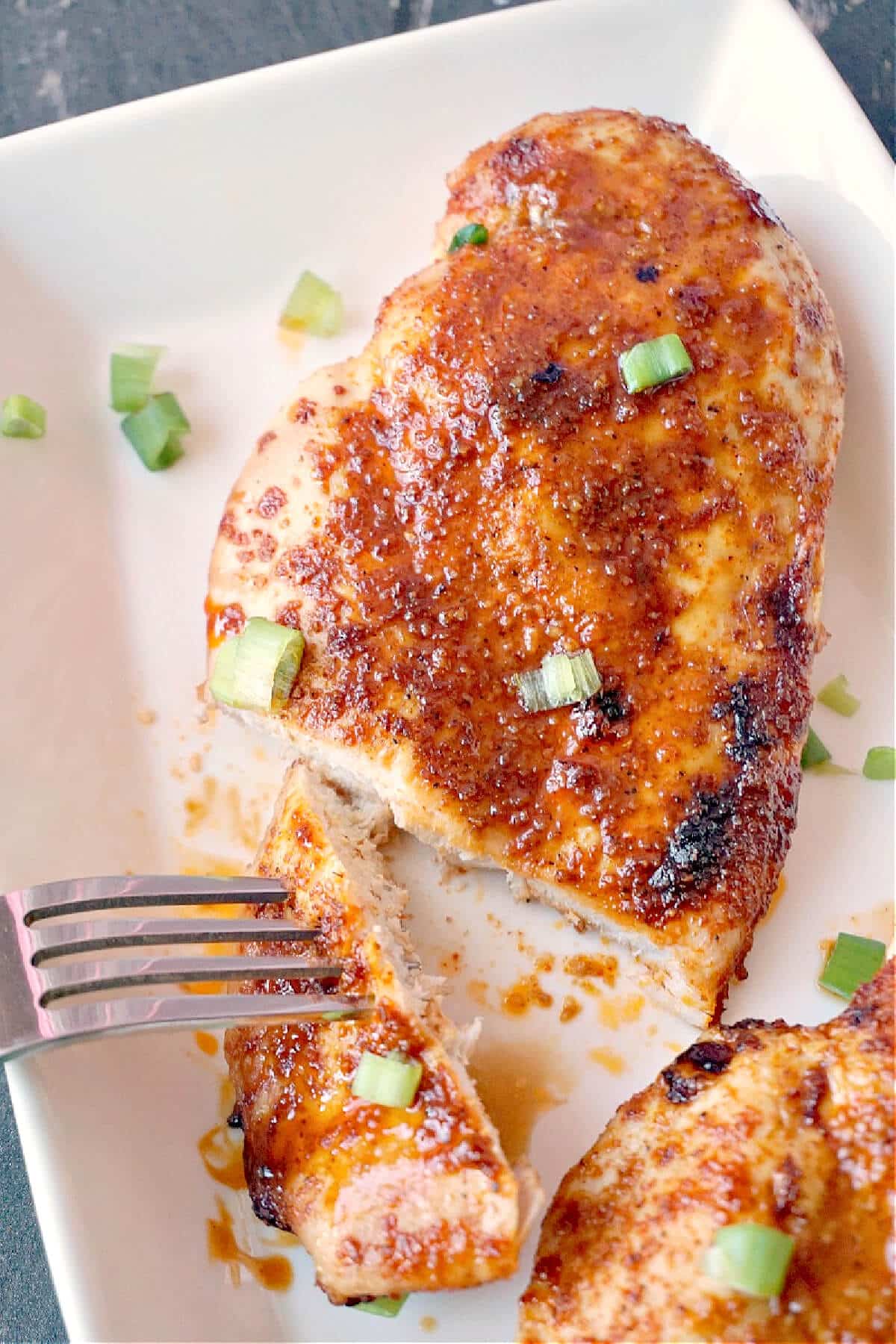 Close-up shoot of a chicken breast on a white plate.