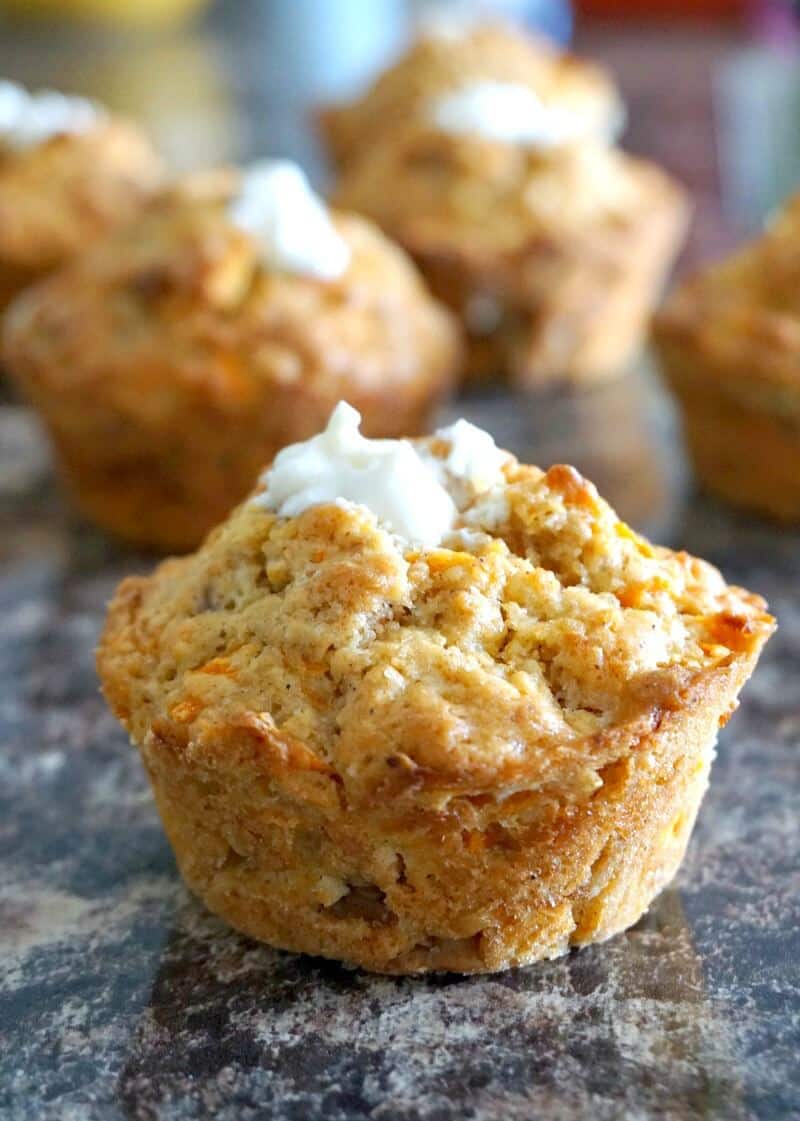 A carrot cake muffin with 3 more muffins in the background