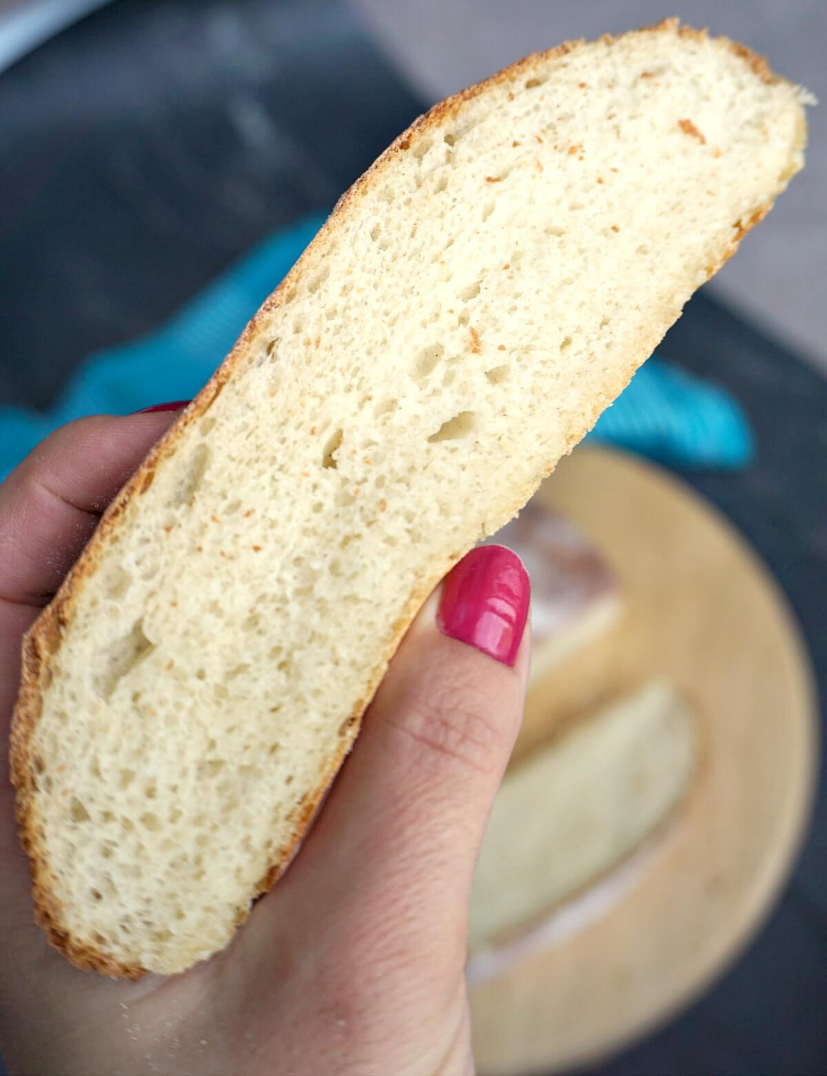 A hand holding a slice of potato bread.
