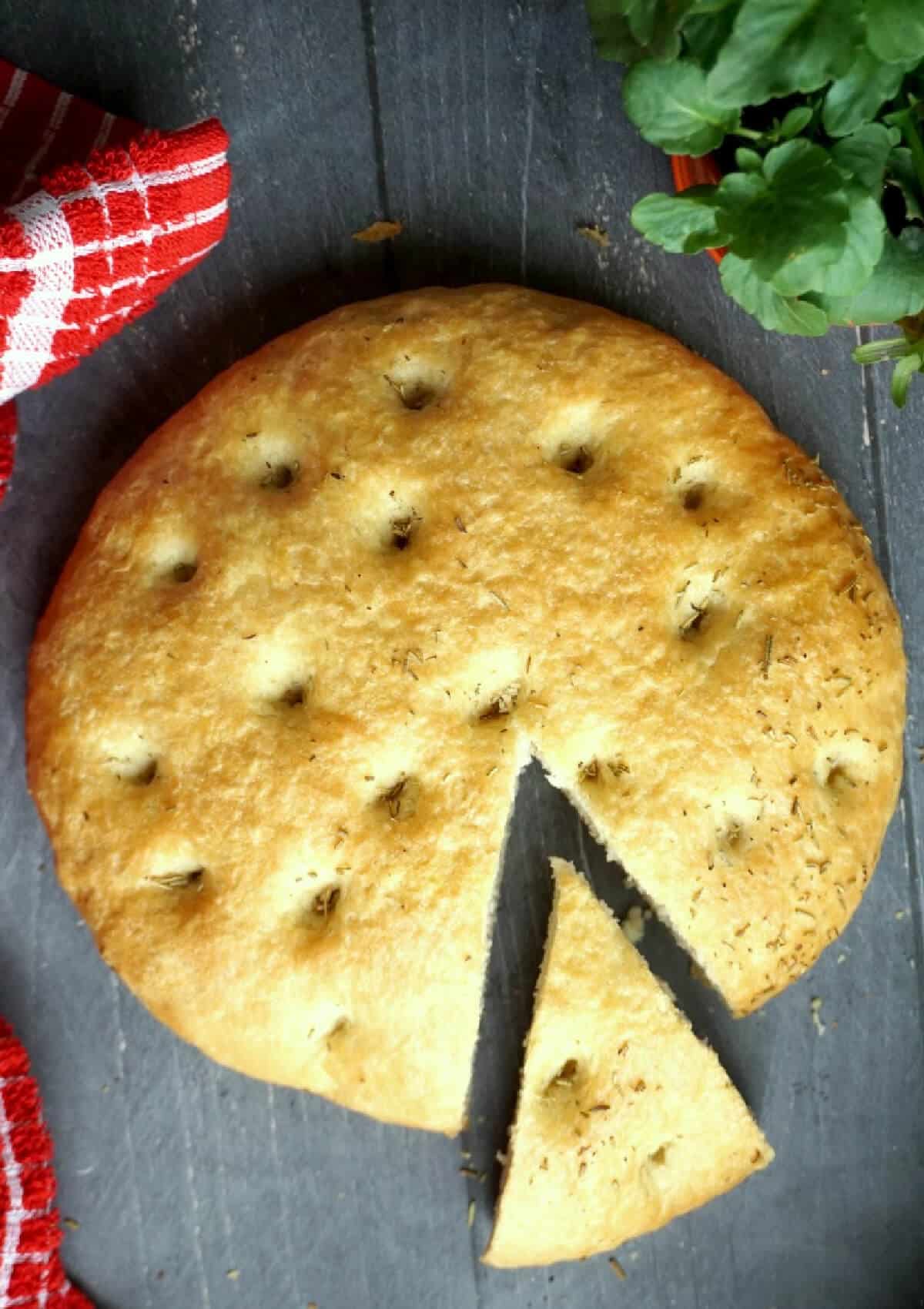 Overhead shoot of a focaccia bread with a slice cut out.