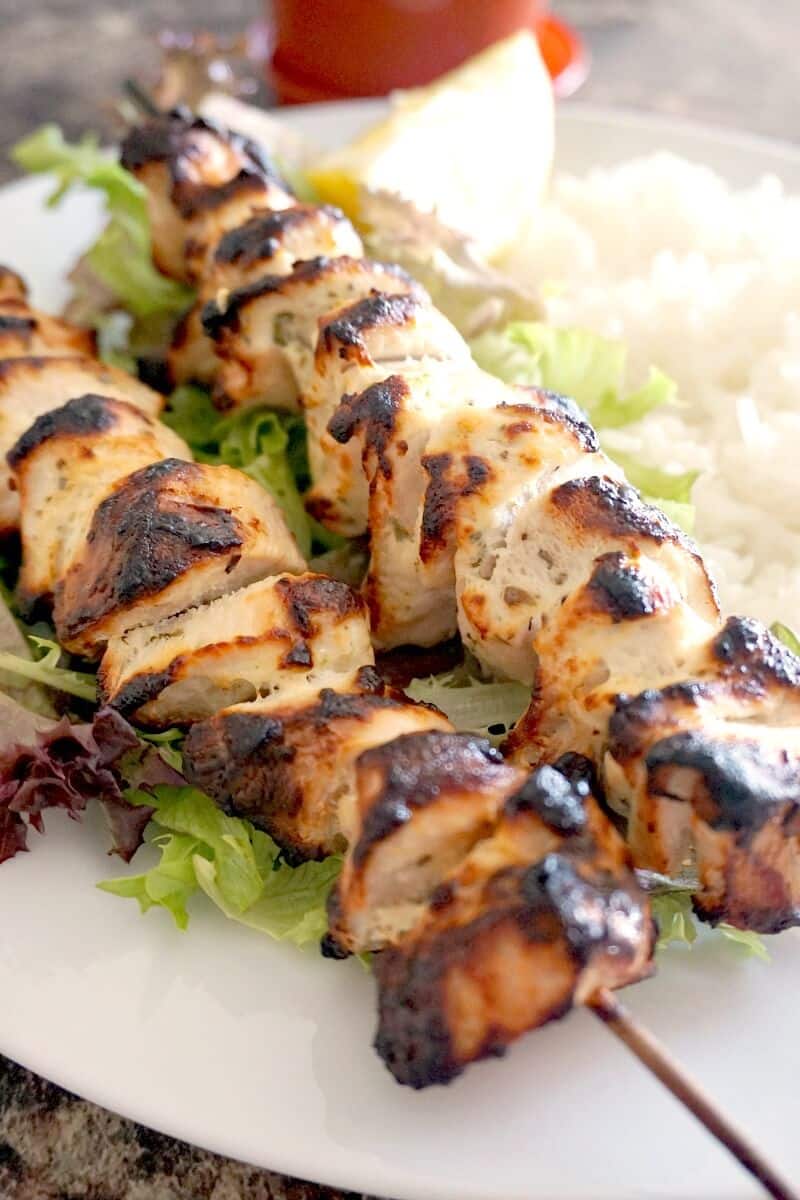 2 chicken kebabs on a bed of salad and rice.