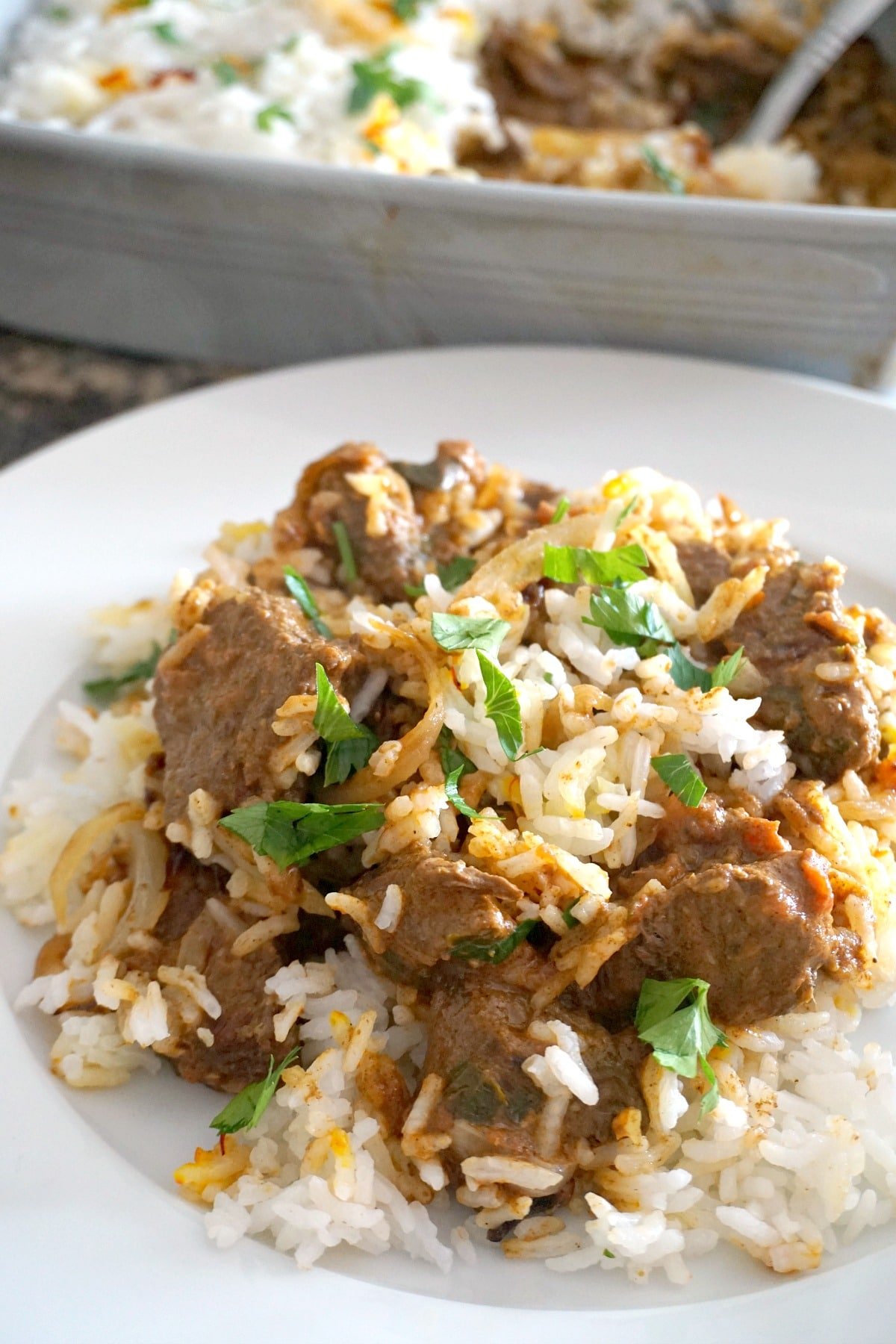 A white plate with beef biryani.