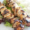 2 chicken kebabs on a bed of rice and salad