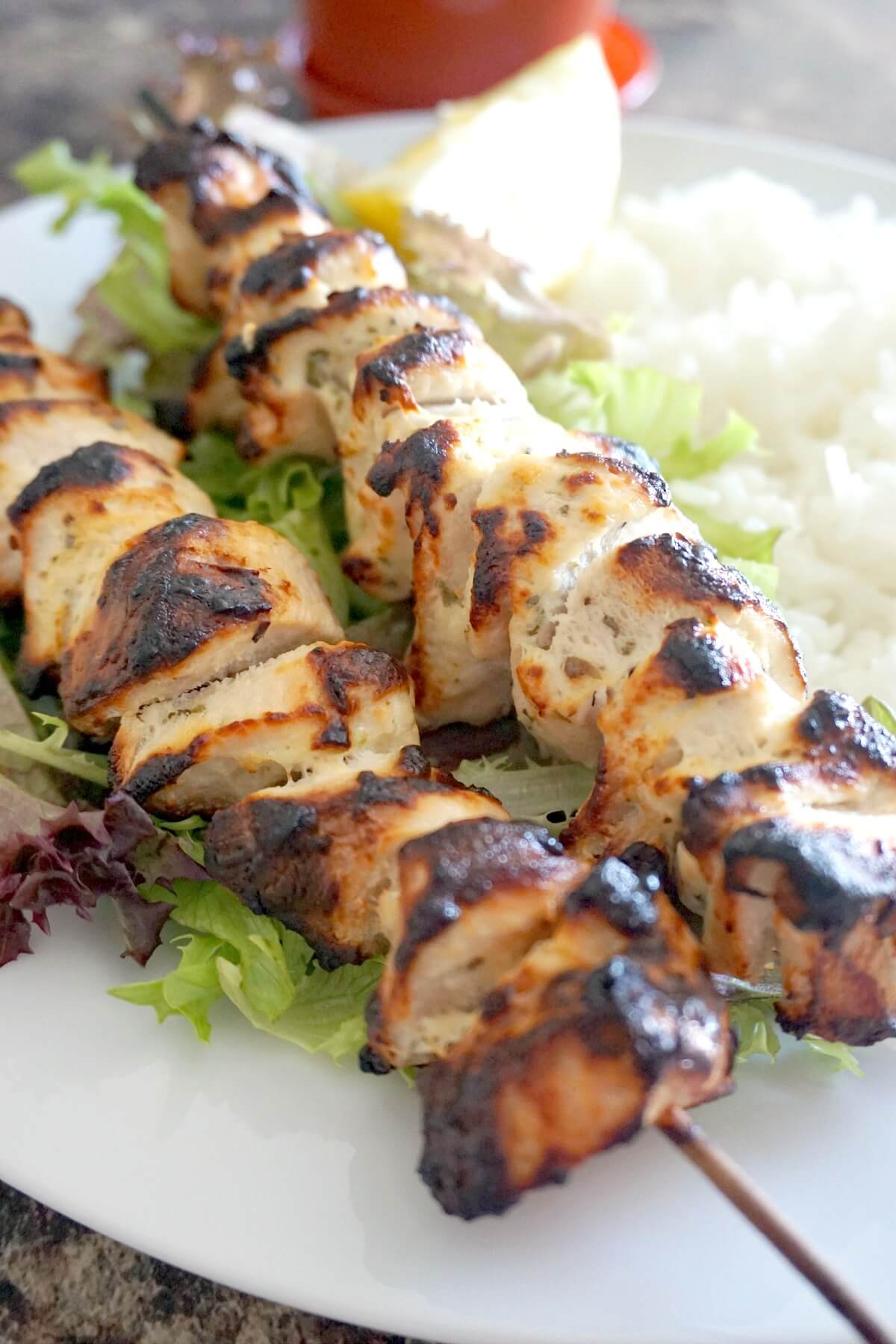 2 chicken kebabs on a bed of salad and rice