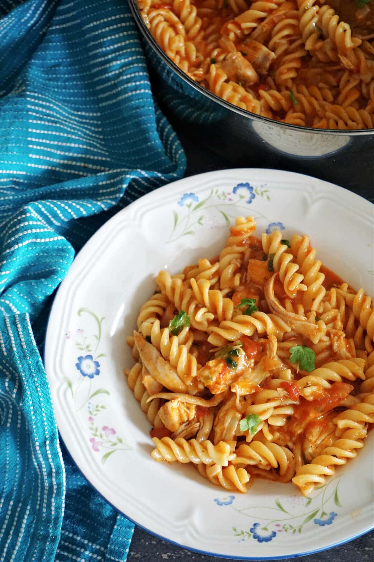 A white plate with pasta with chicken and tomato sauce