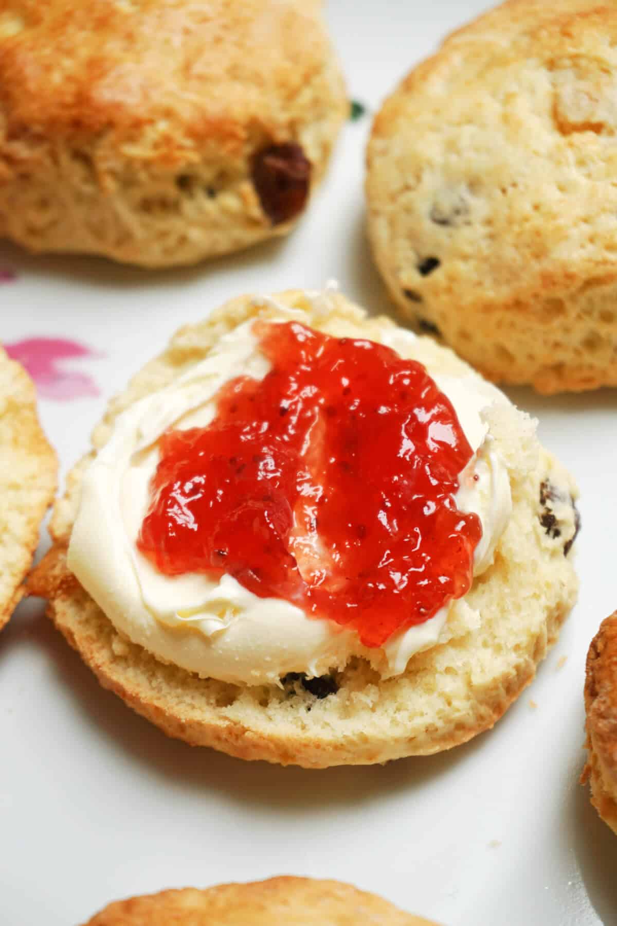 Close-up shoot of a scone with cream and jam.