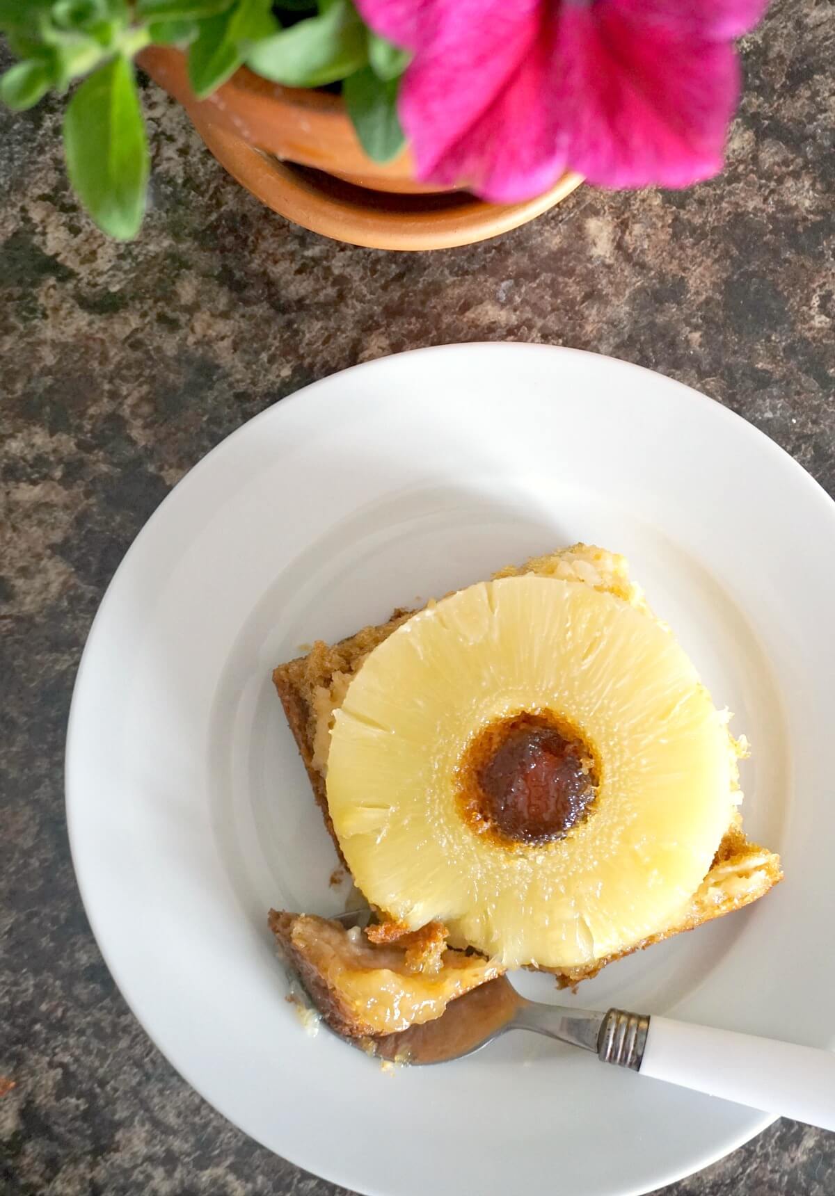 Overhead shoot of a white plate with a slice of pineapple upside down cake.