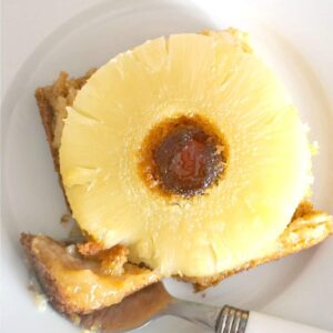 Overhead shoot of a white plate with a slice of pineapple upside down cake