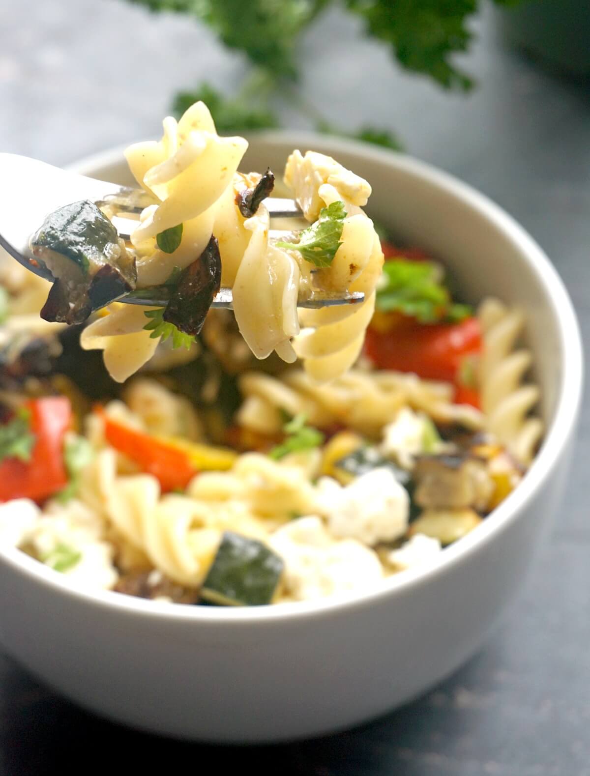 A white bowl with pasta salad with roasted vegetables.