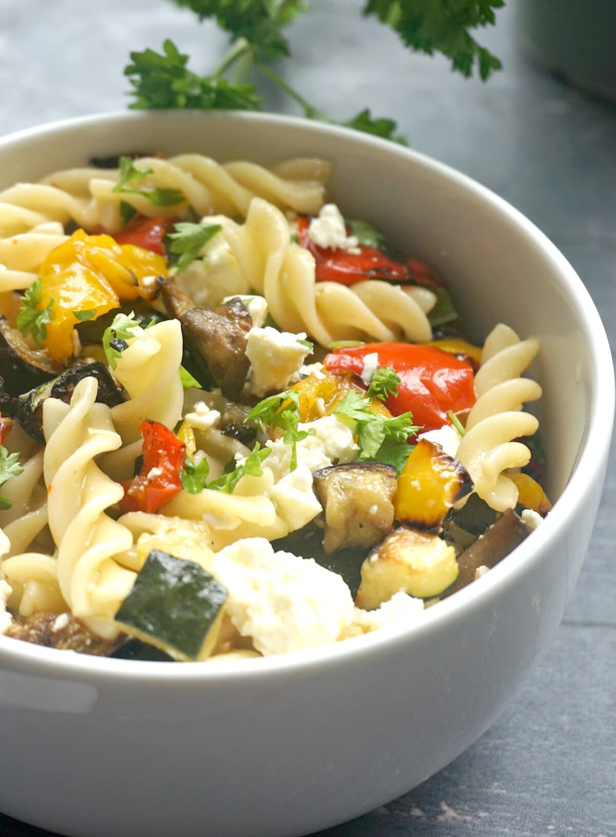 Close-up shoot of a bowl of pasta salad with veggies and feta.