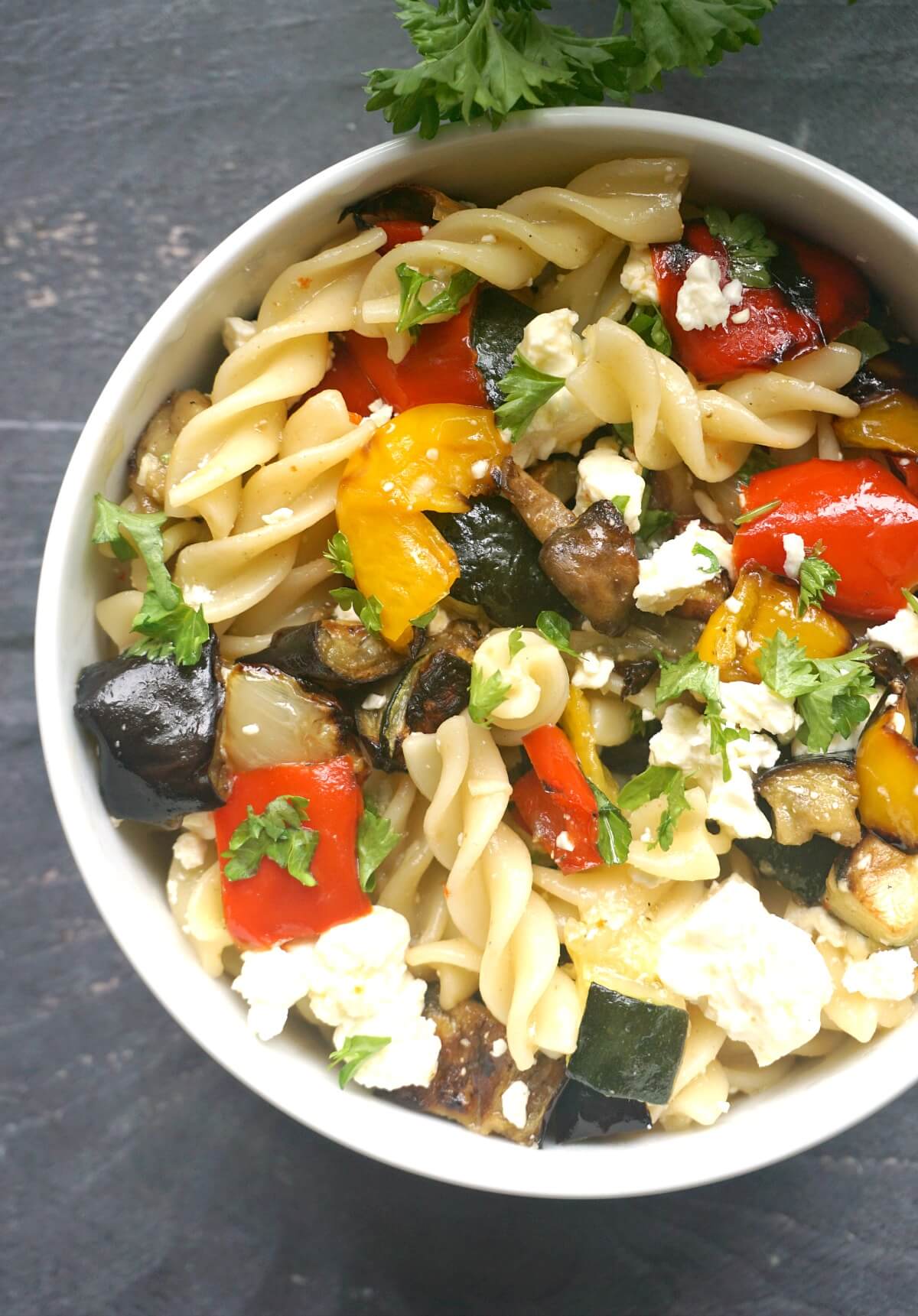 Overhead shoot of a white bowl with roasted veggie pasta salad.