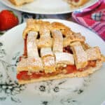 A white patterned plate with a slice of strawberry and rhubarb pie.