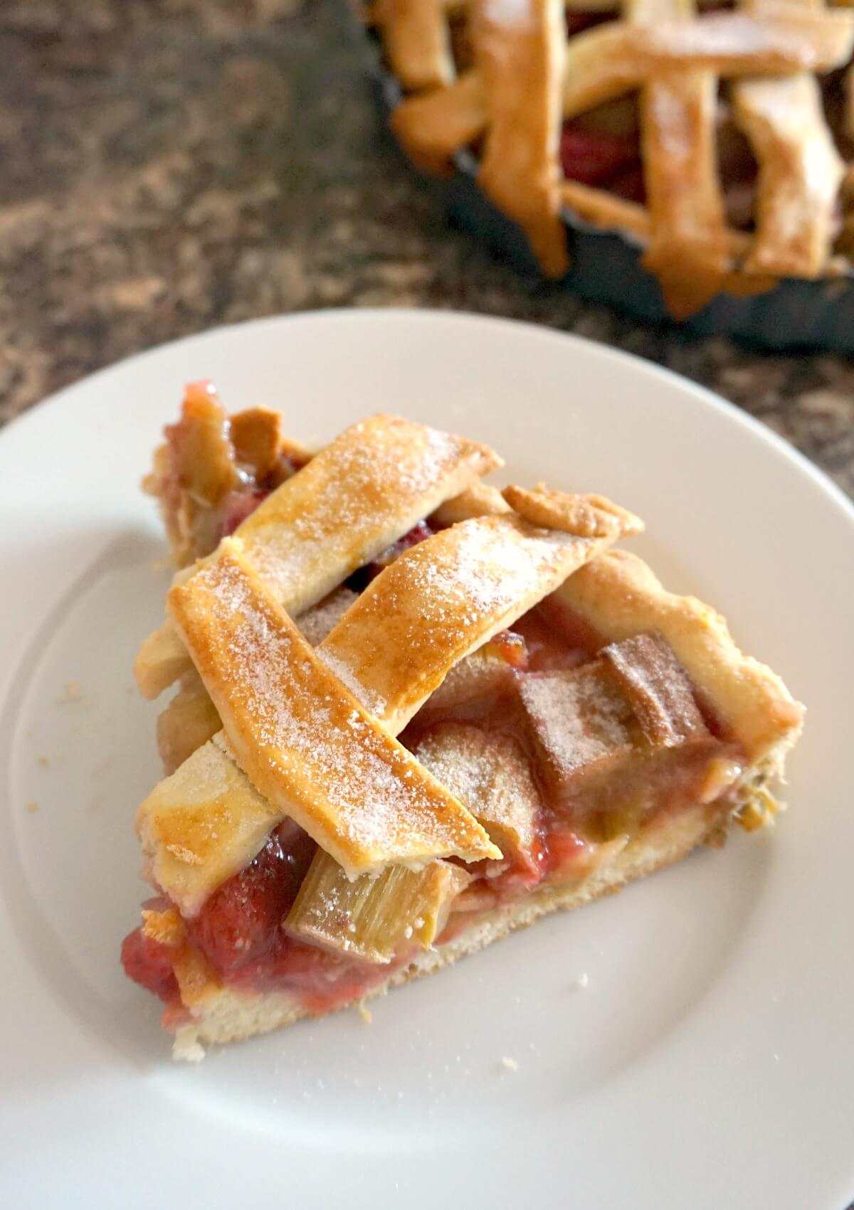 A white plate with a slice of strawberry and rhubarb pie.