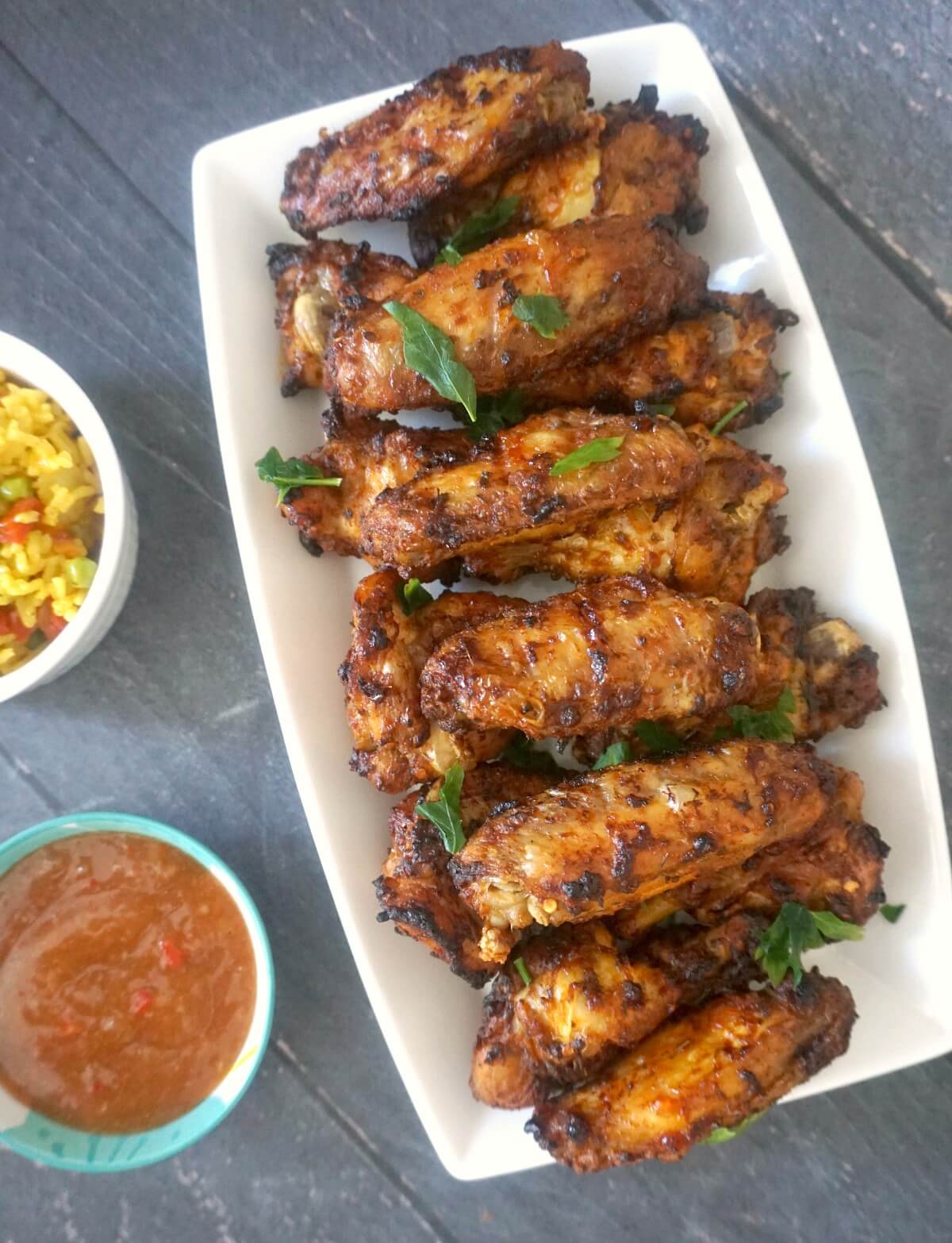 Overhead shoot of a white rectangle plate with peri-peri chicken wings.