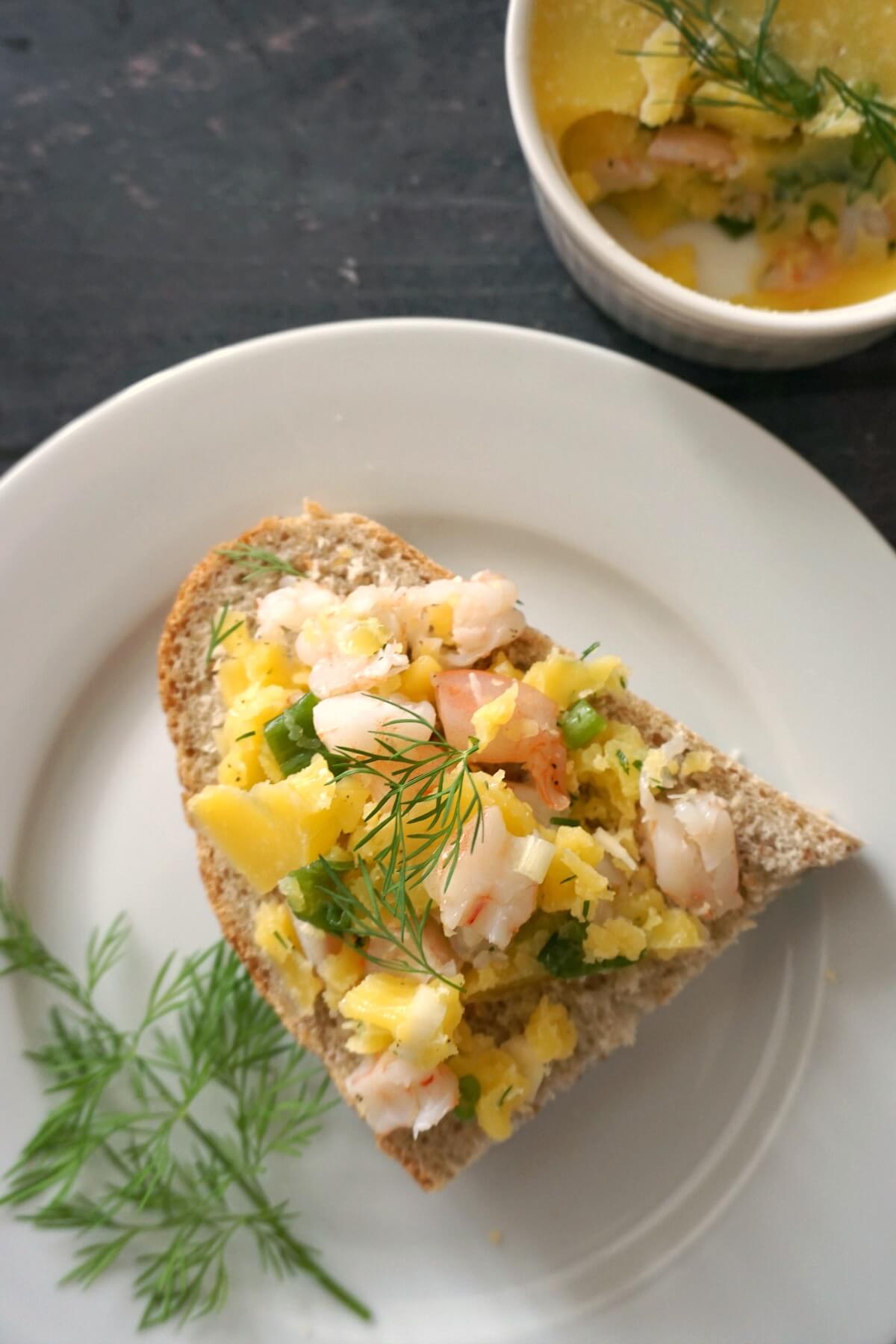 A white plate with a slice of bread and spread with potted shrimp.