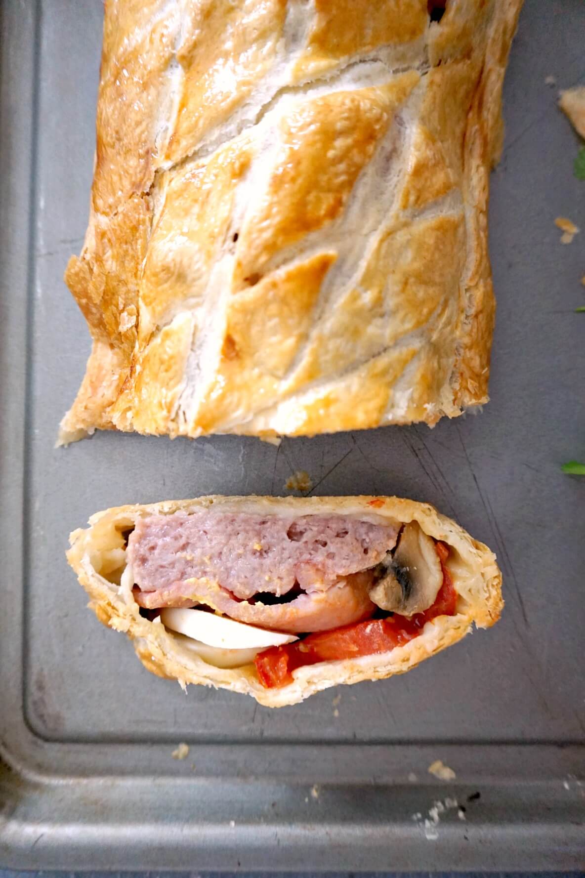 Overhead shoot of a slice of breakfast wellington with the rest of the roll on a baking tray.