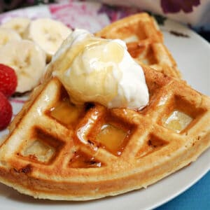 2 waffles on a white plate topped with a dollop of yogurt and honey