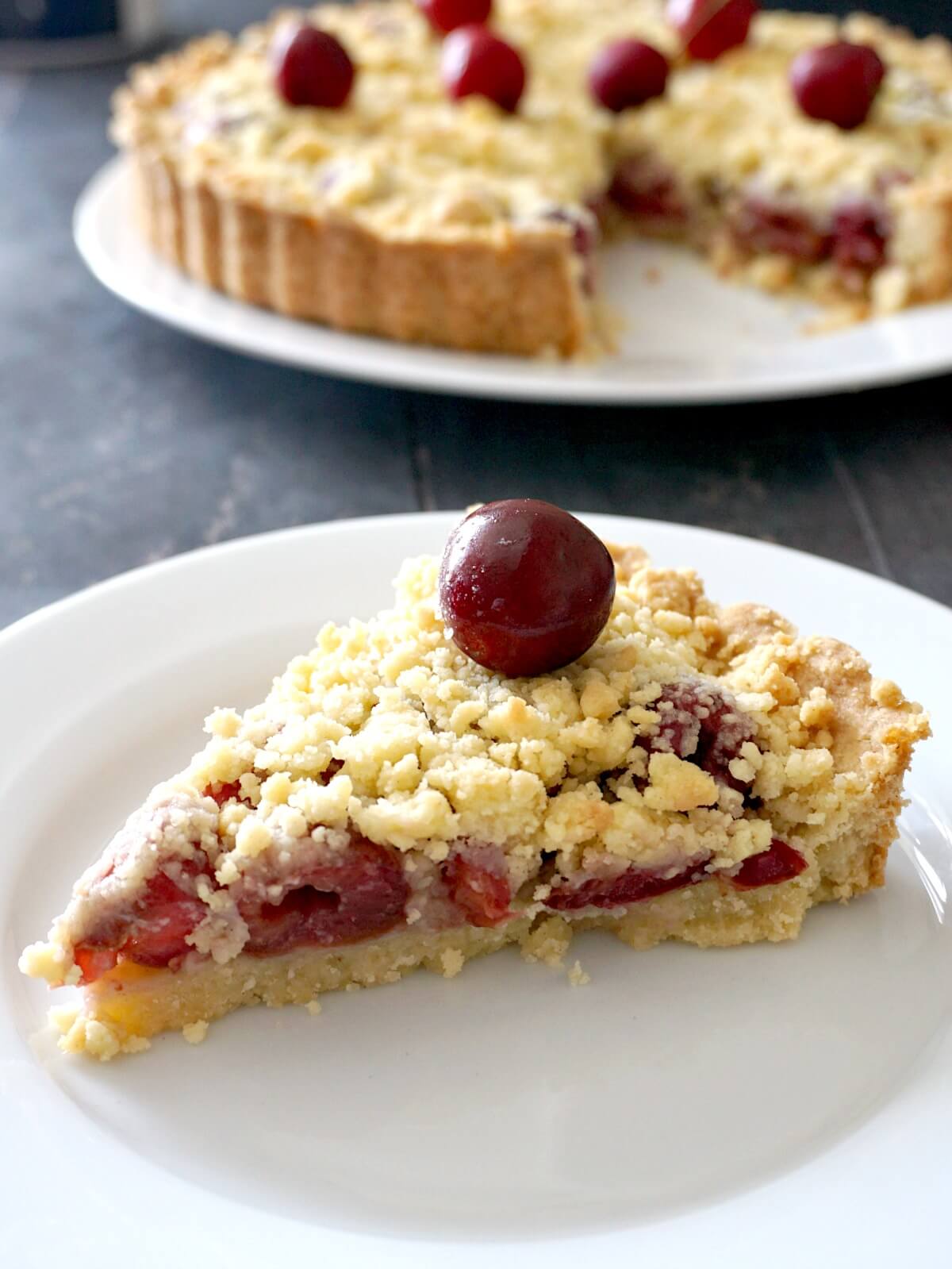 A slice of cherry crumb pie on a white plate.