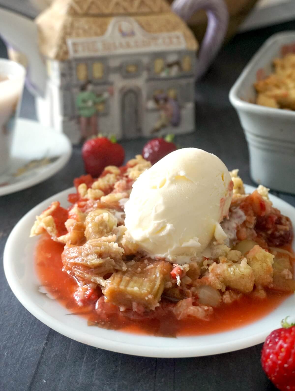 A white plate with fruit crumble topped with a scoop of ice cream.