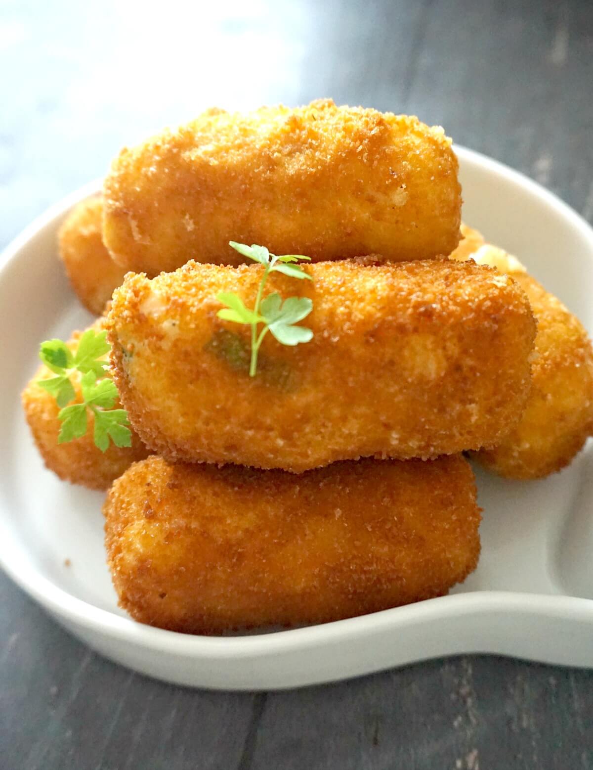 A white bowl with 5 potato croquettes.