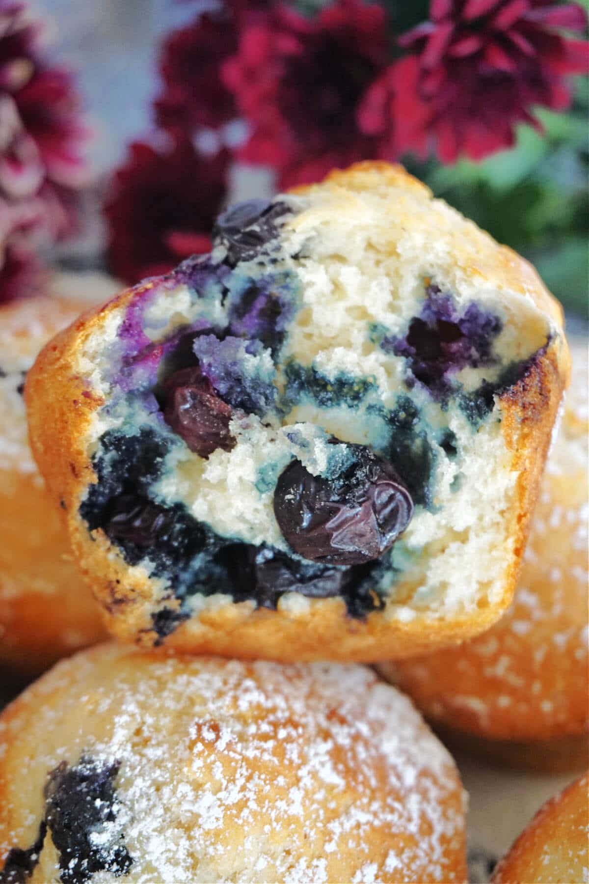 Close-up shot of half a blueberry muffin on top of other muffins