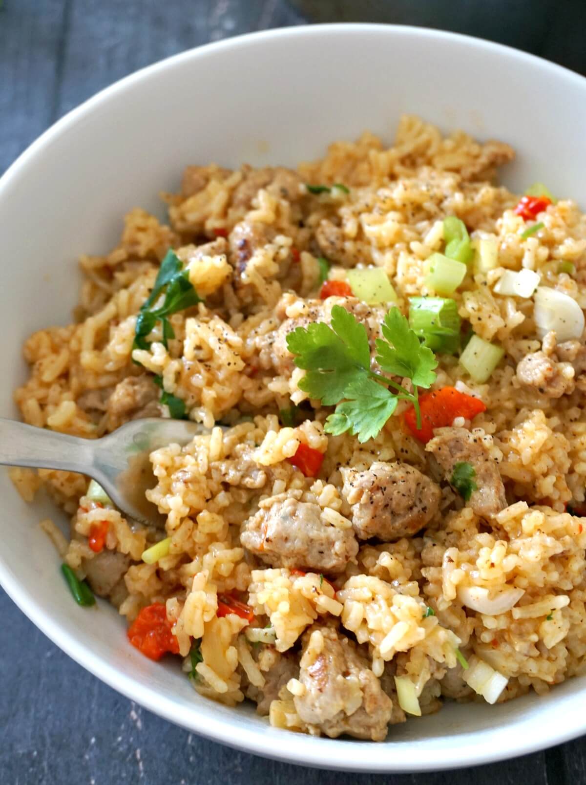 A white bowl of sausage veggies and rice.