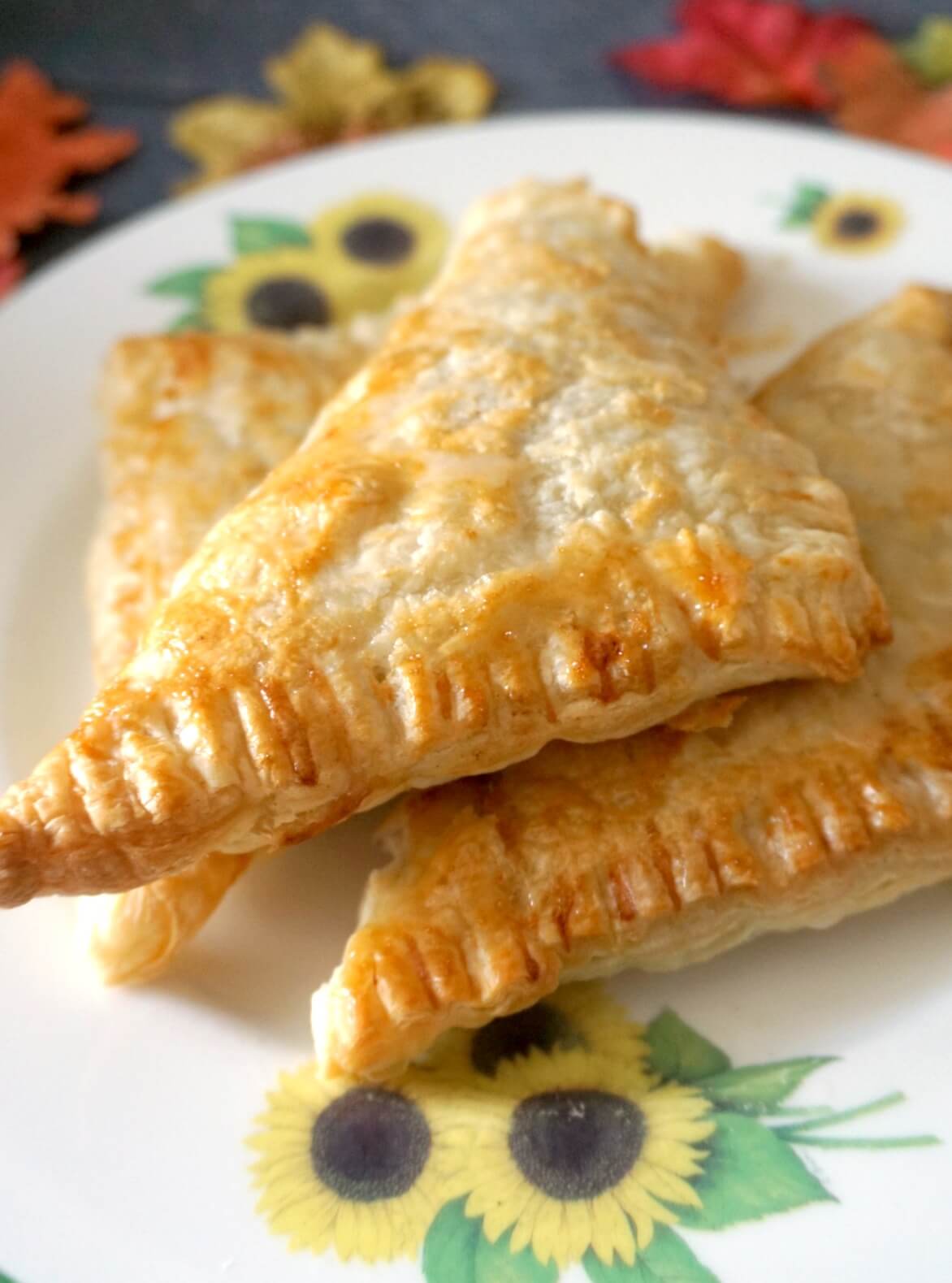 A stack of 3 apple turnovers on a large plate.