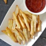 Overhead shoot of a white rectangle plate with fries and a ramekin of ketchup