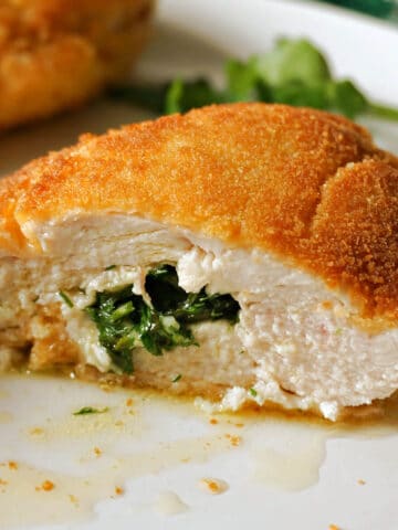 Half of a chicken Kiev on a white plate.