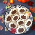 Overhead shoot of a plate with 9 linzer cookies in the shape of pumpkins