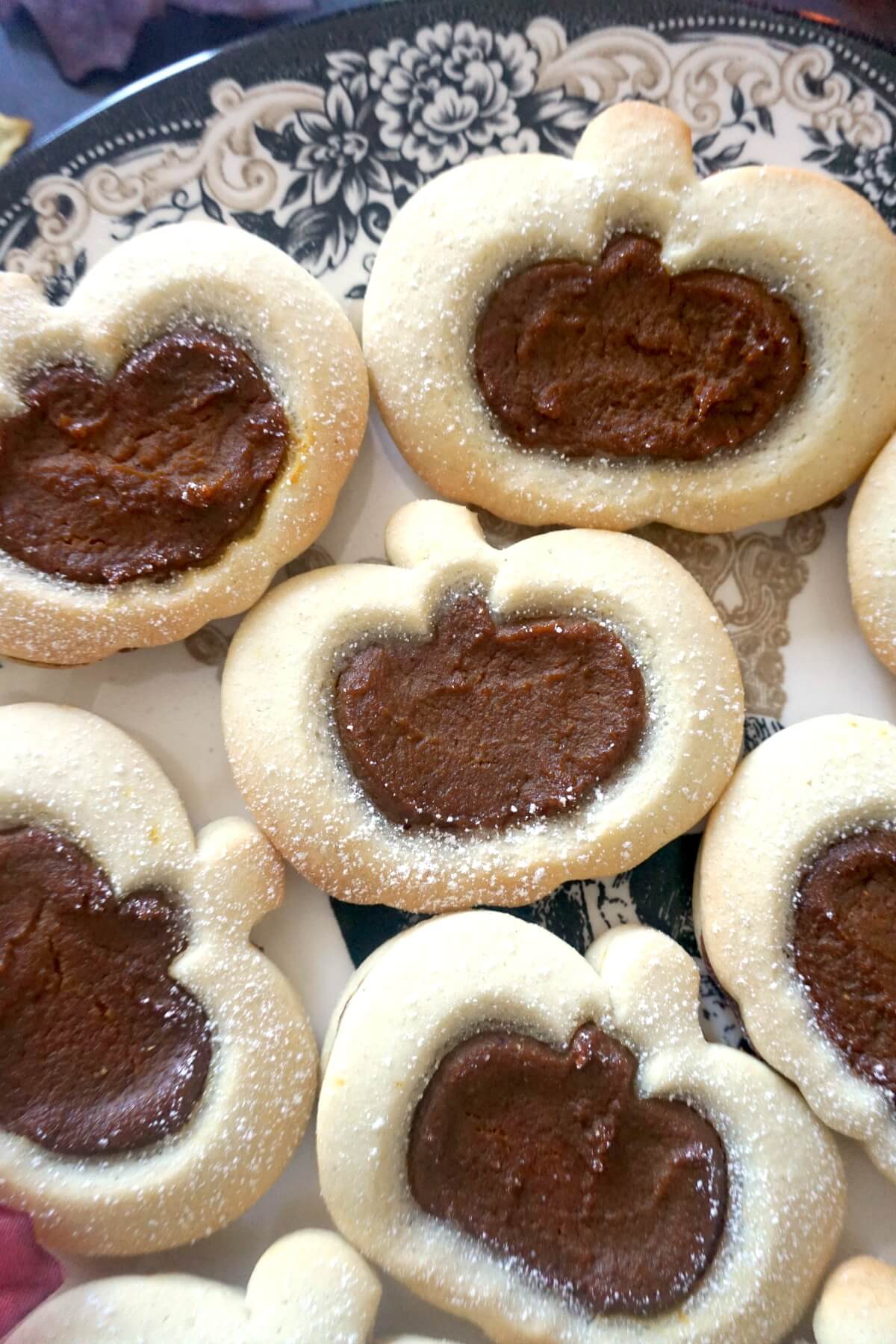 Close-up shoot of 6 pumpkin linzer cookies on a plate.