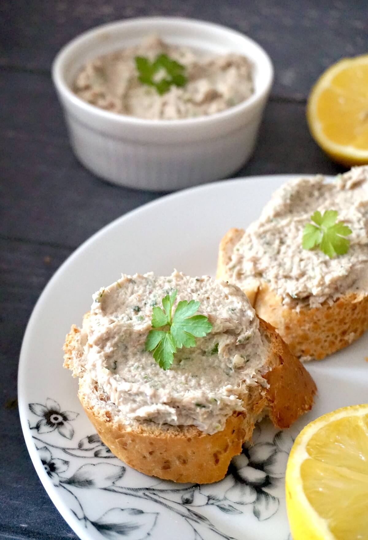 2 slices of bread spread with mackerel pate on a white plate.