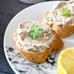 2 slices of bread with pate on them and a parsley leaf on top
