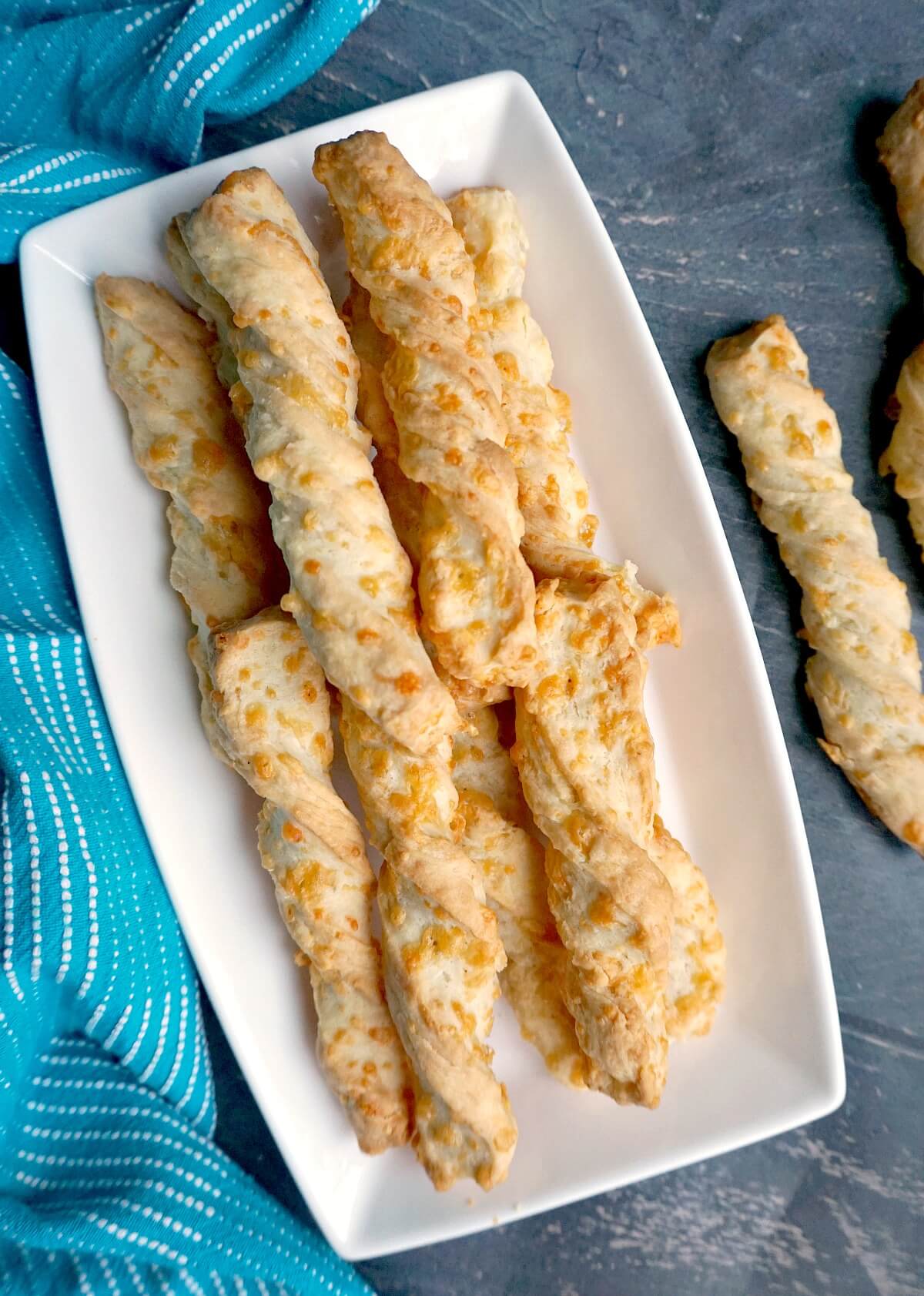 Overhead shoot of a white rectangle plate with cheese twists.