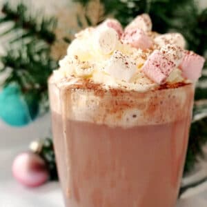 A glass with hot chocolate with marshmallows and cream