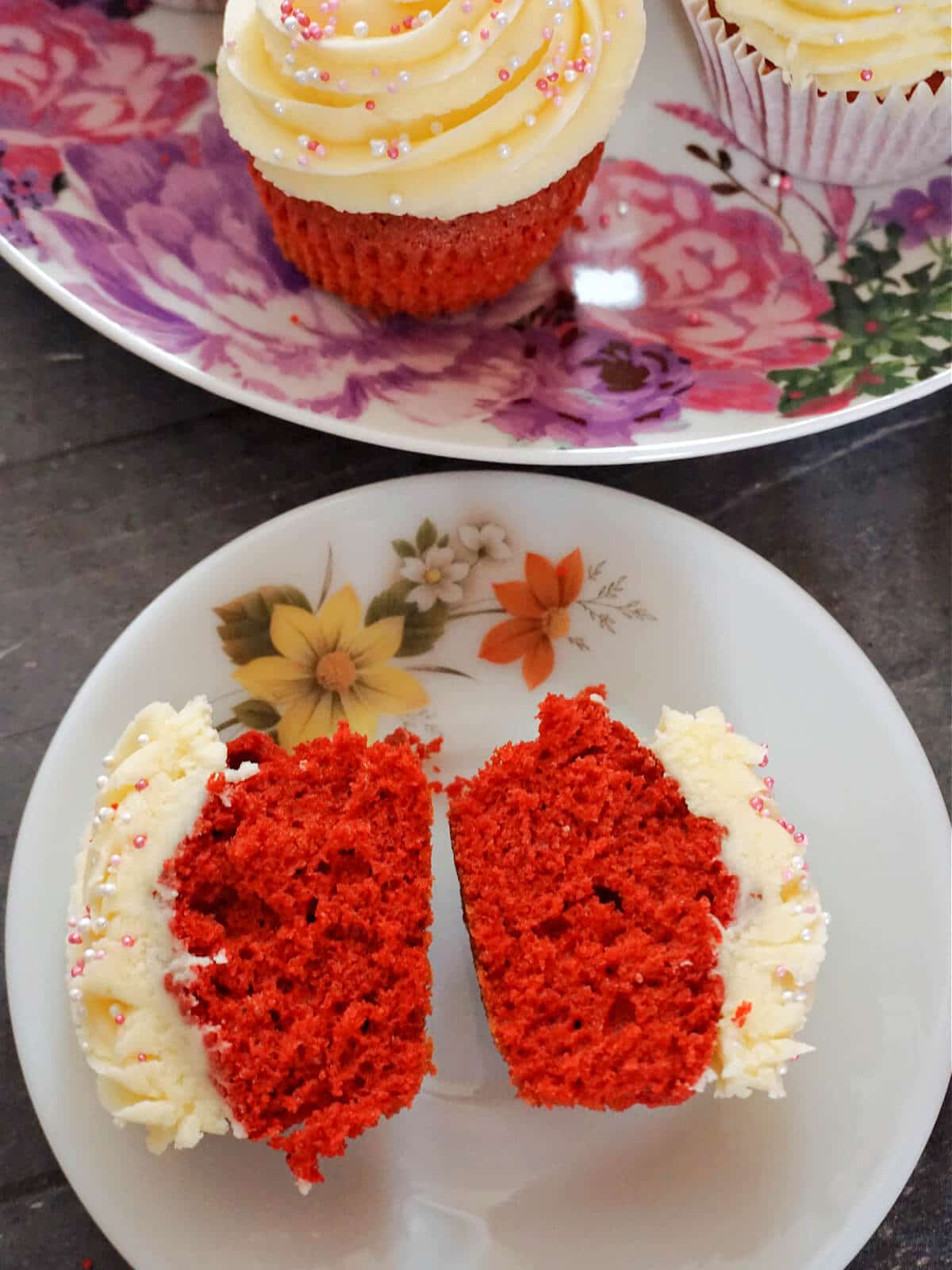 Overhead shoot of a white plate with 2 halves of a red velvet cupcake.