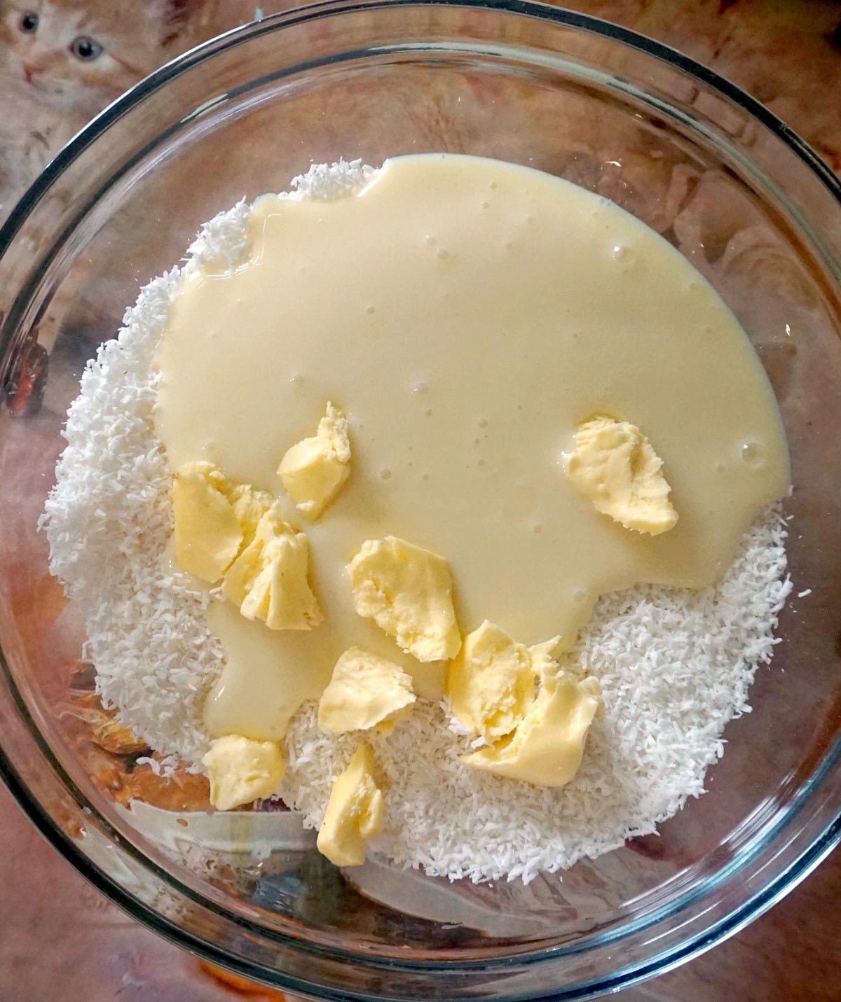 A glass bowl of desiccated coconut, condensed milk and butter to make snowman truffles.