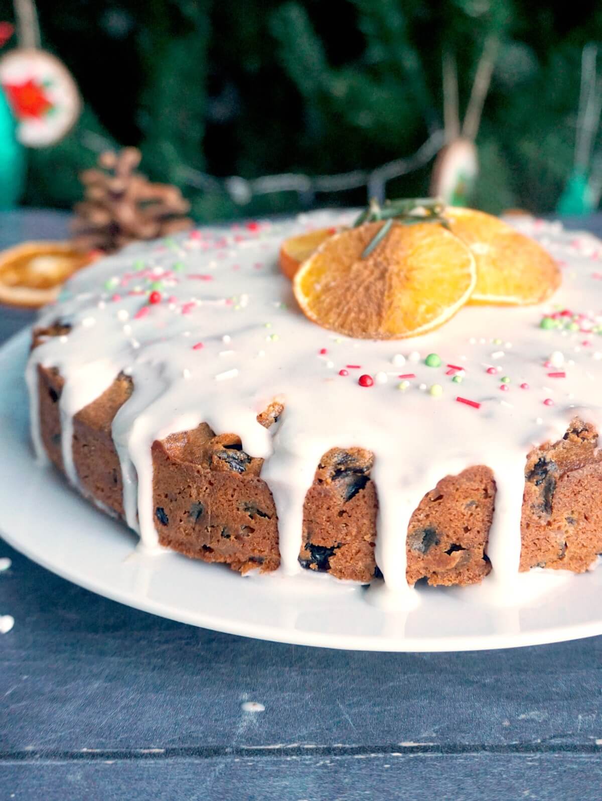 A Christmas cake with icing on top and dried orange slices