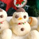 A snowman truffle with other coconut balls around on a white plate